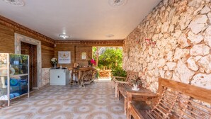 A wooden interior with a stone wall, a wooden bench, a small table, and a cabinet. - Hotel Vista de Aguilas Ecolodge (Pedernales)
