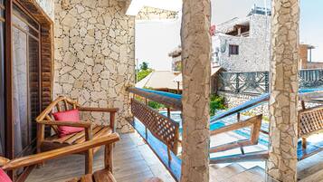 Relax on the balcony with a view of the pool, surrounded by a stone balustrade and comfortable seating.