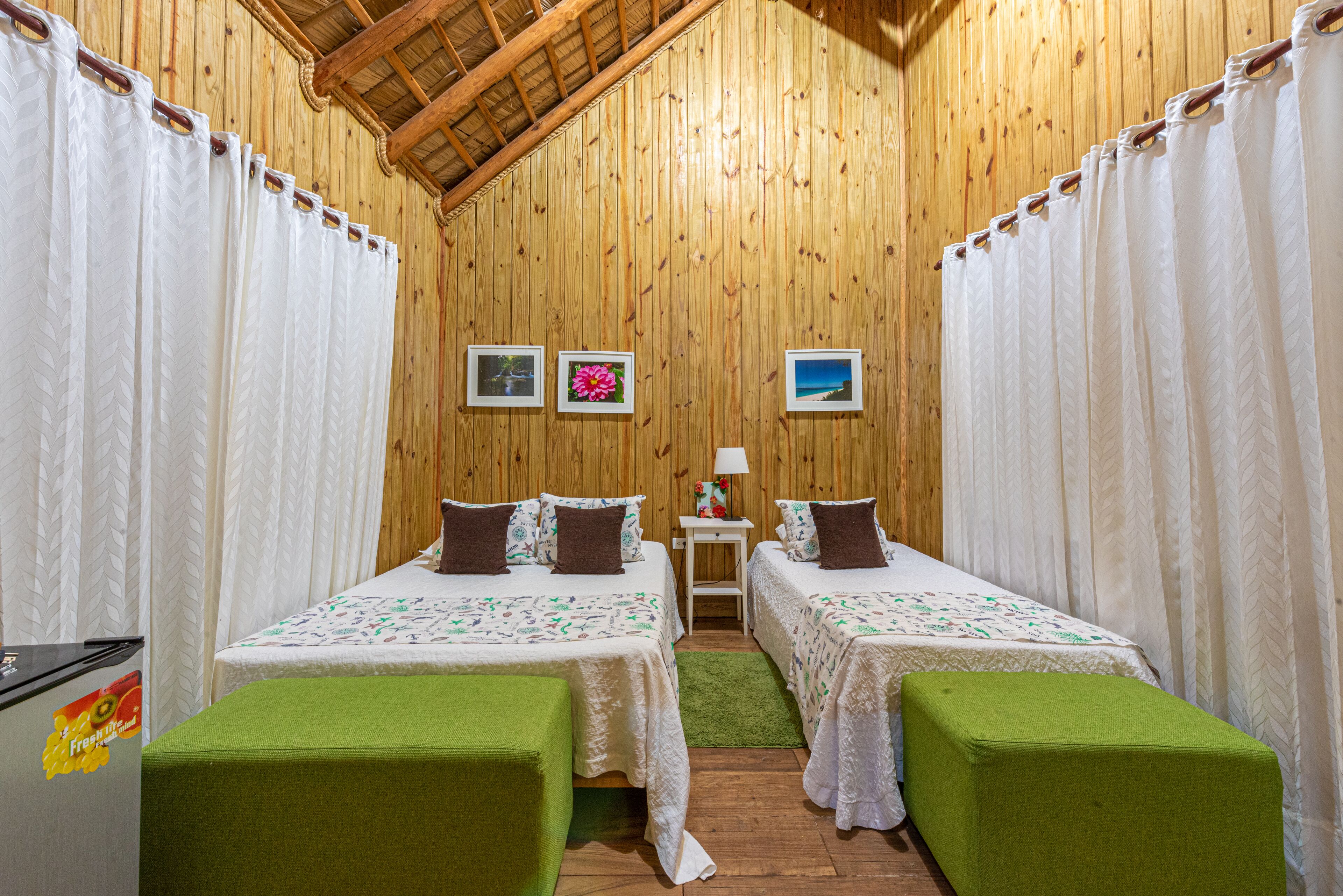 A room with two beds, a small table, and a refrigerator.