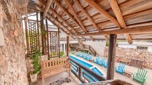 A wooden deck with a pool, stone walls, and outdoor seating. - Hotel Vista de Aguilas Ecolodge (Pedernales)