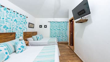 A bedroom with two beds, a TV mounted on the wall, and a wooden floor.