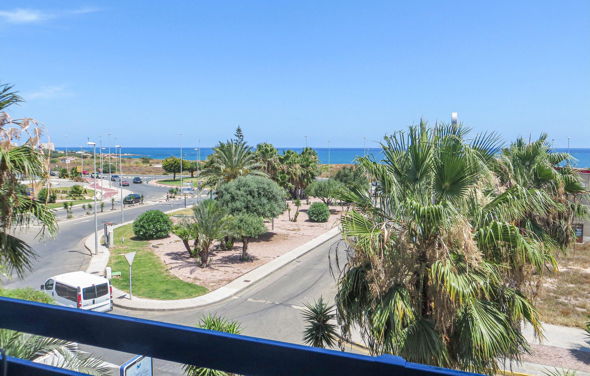 A coastal road with palm trees and a view of the sea.