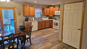 A kitchen with wooden cabinets, a dining table with chairs, a microwave, and an oven. - 3 Bedroom home with rear deck and covered front porch. (Delancey)