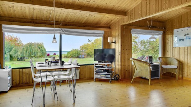 Une cabane en bois comprenant un coin repas, un téléviseur et des chaises en osier.