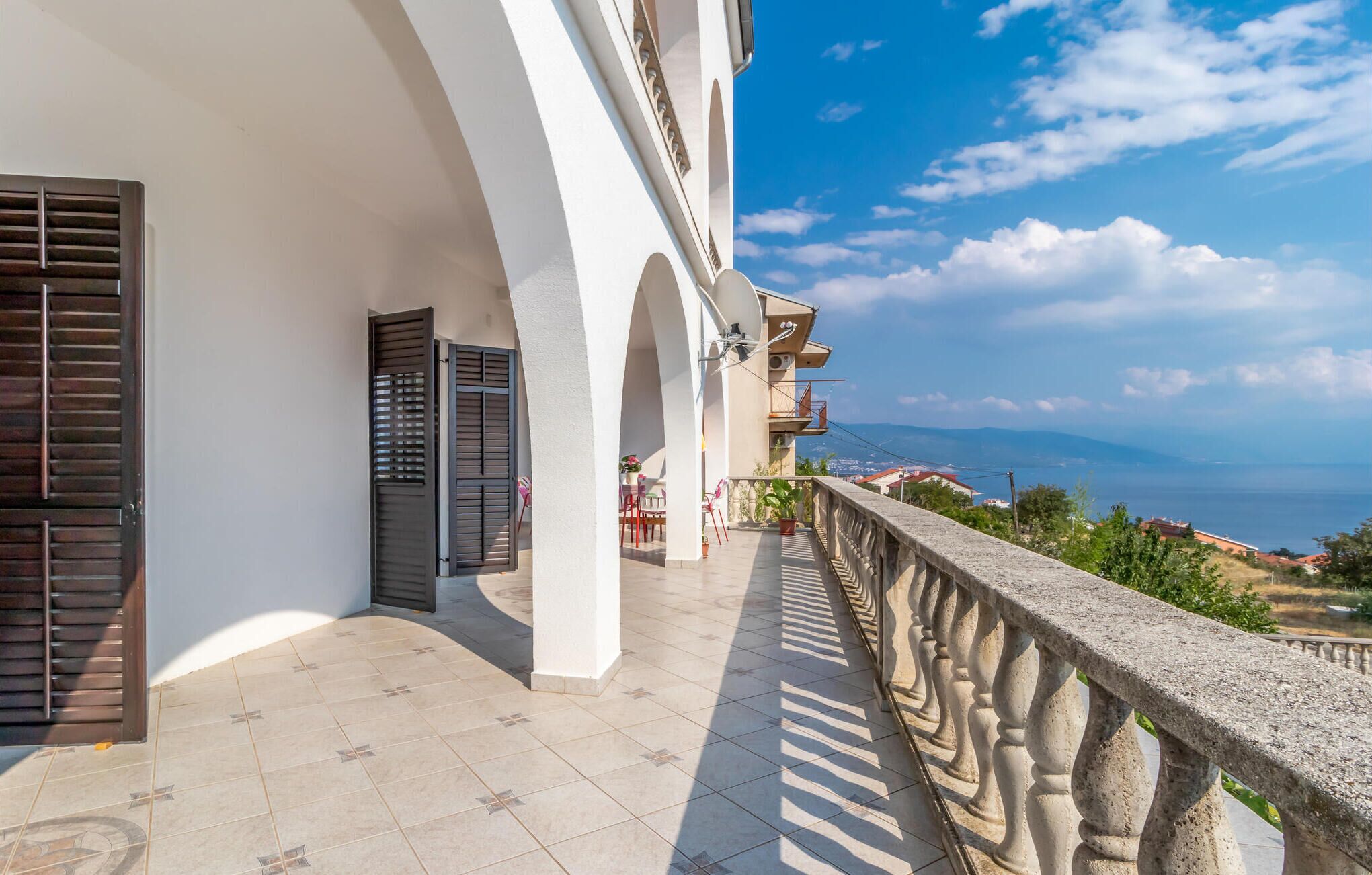 Un balcon doté d’une balustrade en pierre, offrant une vue sur la côte.