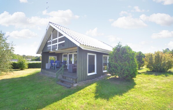Situated in a peaceful natural setting, this cabin features a front porch with two chairs and a table.
