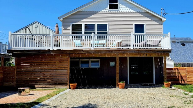 Ein zweigeschossiges Haus mit Balkon, Garage und kleiner Veranda.