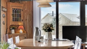 A wooden interior with a round table, a TV, and a window with a view of a building.