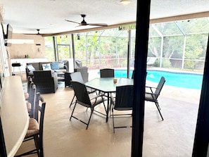 Un patio cubierto con piscina, mobiliario exterior y ventilador de techo.
