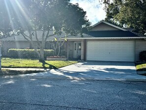 A residential house with a garage, driveway, and lawn. - Family Friendly heated pool Home 2000sqft <br>“NO parties” (Palm Harbor)