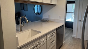 Een moderne keuken met witte kastjes, een marmeren aanrechtblad en een inbouwvaatwasser.