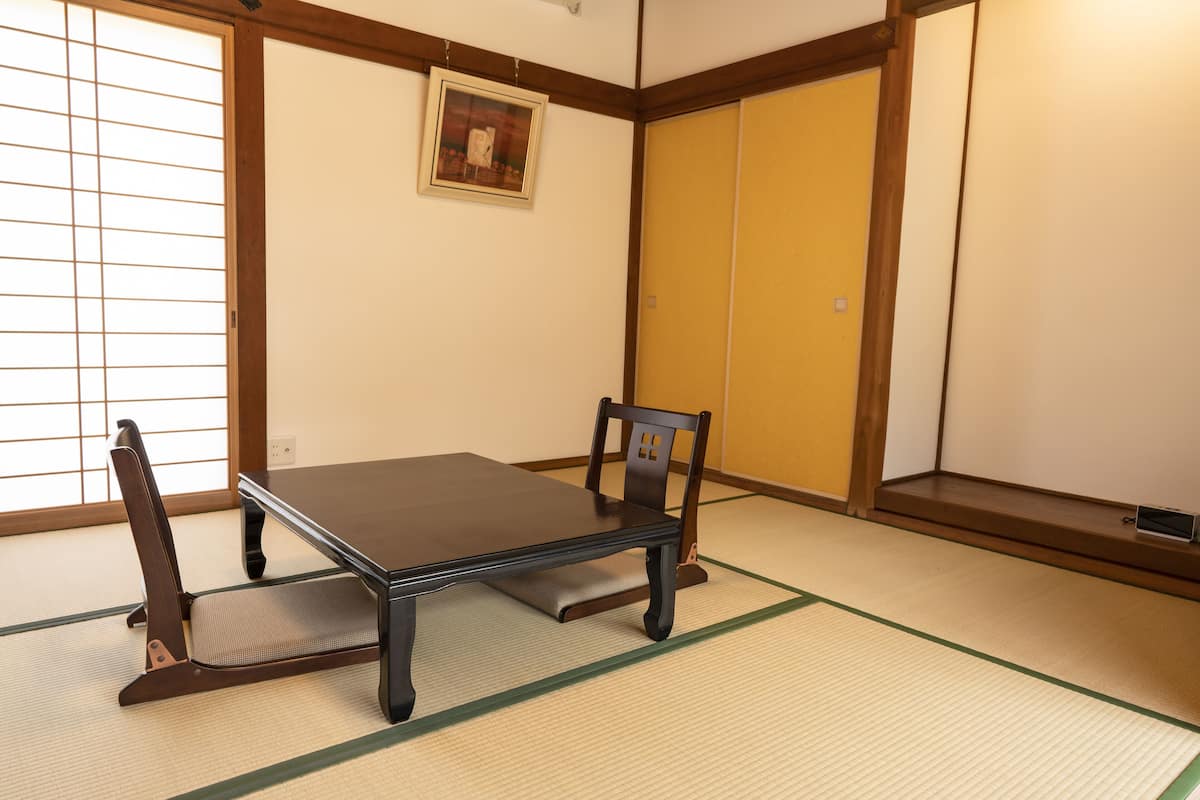 Una habitación japonesa tradicional con suelo de tatami, una mesa baja y un par de sillas.