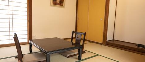 Una habitación japonesa tradicional con suelo de tatami, una mesa baja y un par de sillas.