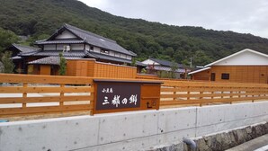 Un edificio tradicional japonés con una valla de madera al frente y un cartel que indica una zona de estacionamiento.