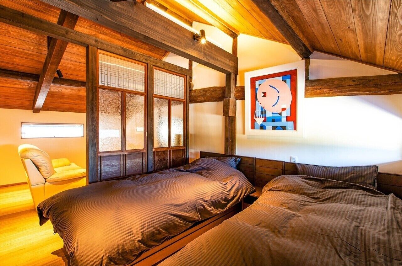Ein Schlafzimmer mit Holzbalken, einem Bett, einem Stuhl und einem Fenster mit Blick.