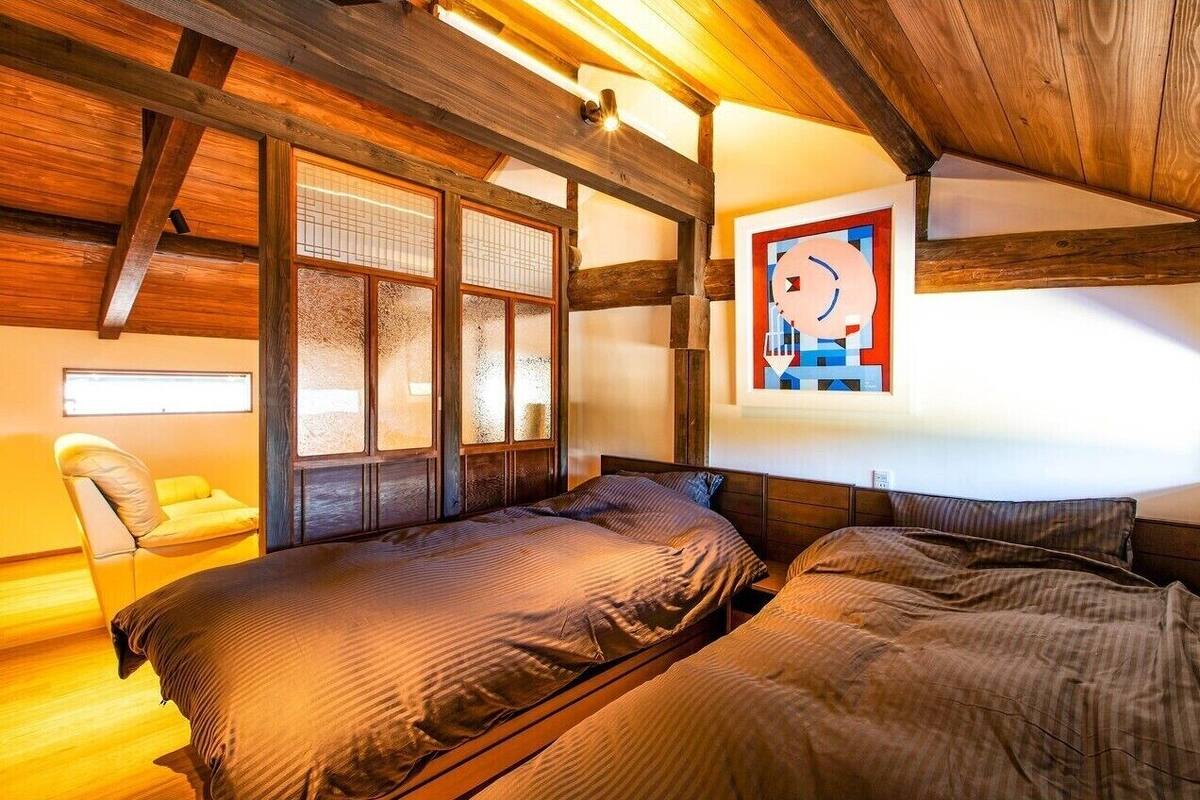 Un dormitorio con vigas de madera, una cama, una silla y un ventanal con vistas.