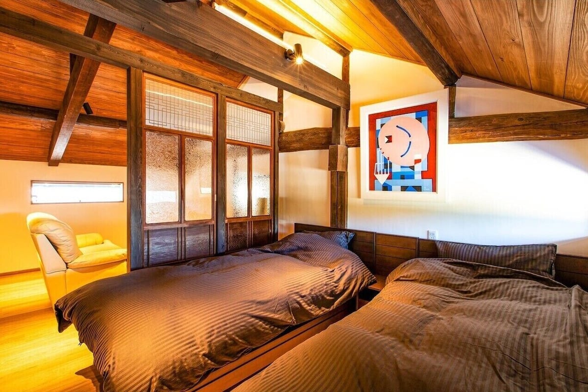 Un dormitorio con vigas de madera, una cama, una silla y un ventanal con vistas.