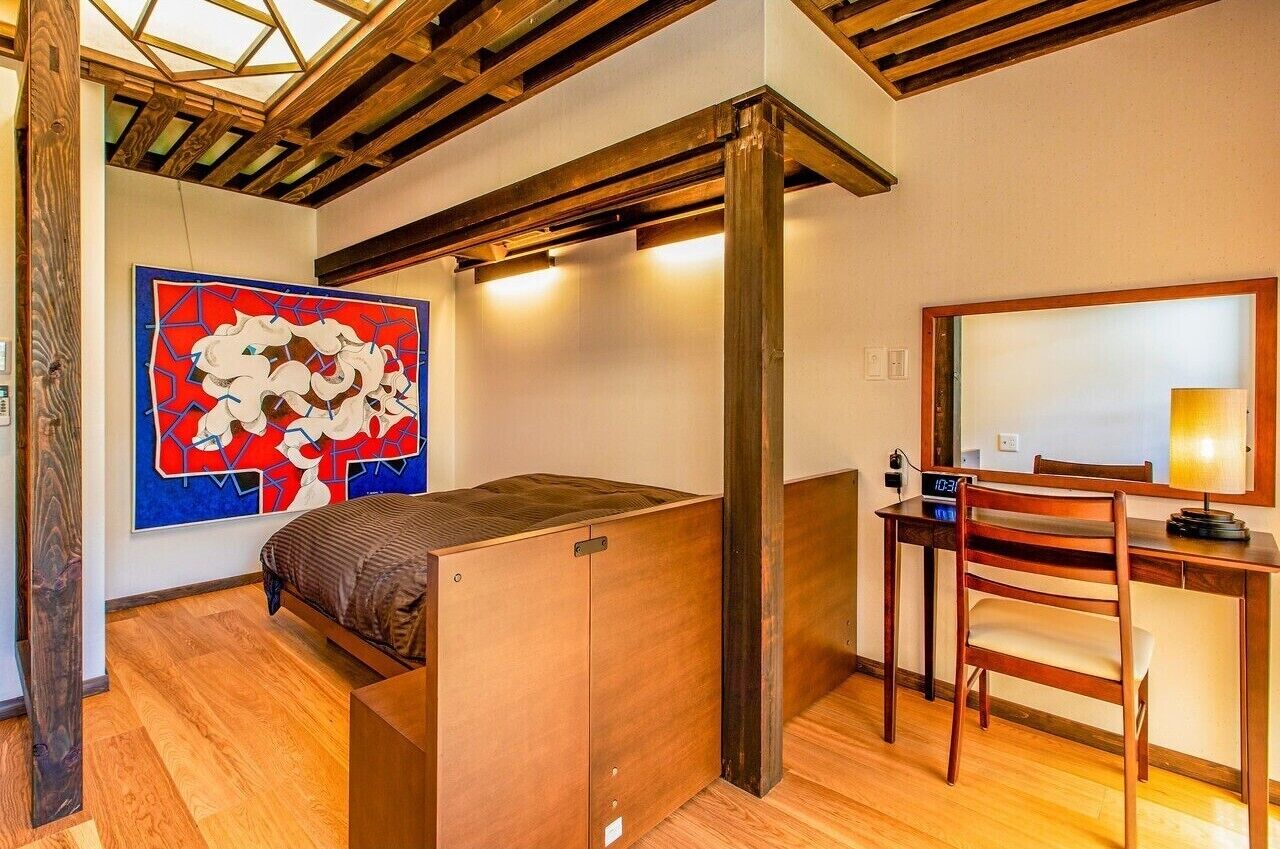 Ein kleines Zimmer mit Bett, Schreibtisch und Stuhl.