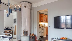 Una sala de estar con chimenea, un comedor con sillas, una cocina visible a través de un vano abierto y un televisor de pantalla plana montado en la pared.
