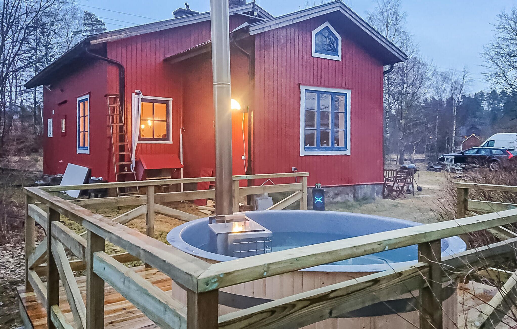 Ein rotes Haus mit einer Holzterrasse und einem Whirlpool.