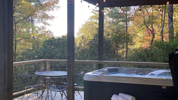 Un bain à remous avec une terrasse en bois, des chaises en métal et une rambarde.