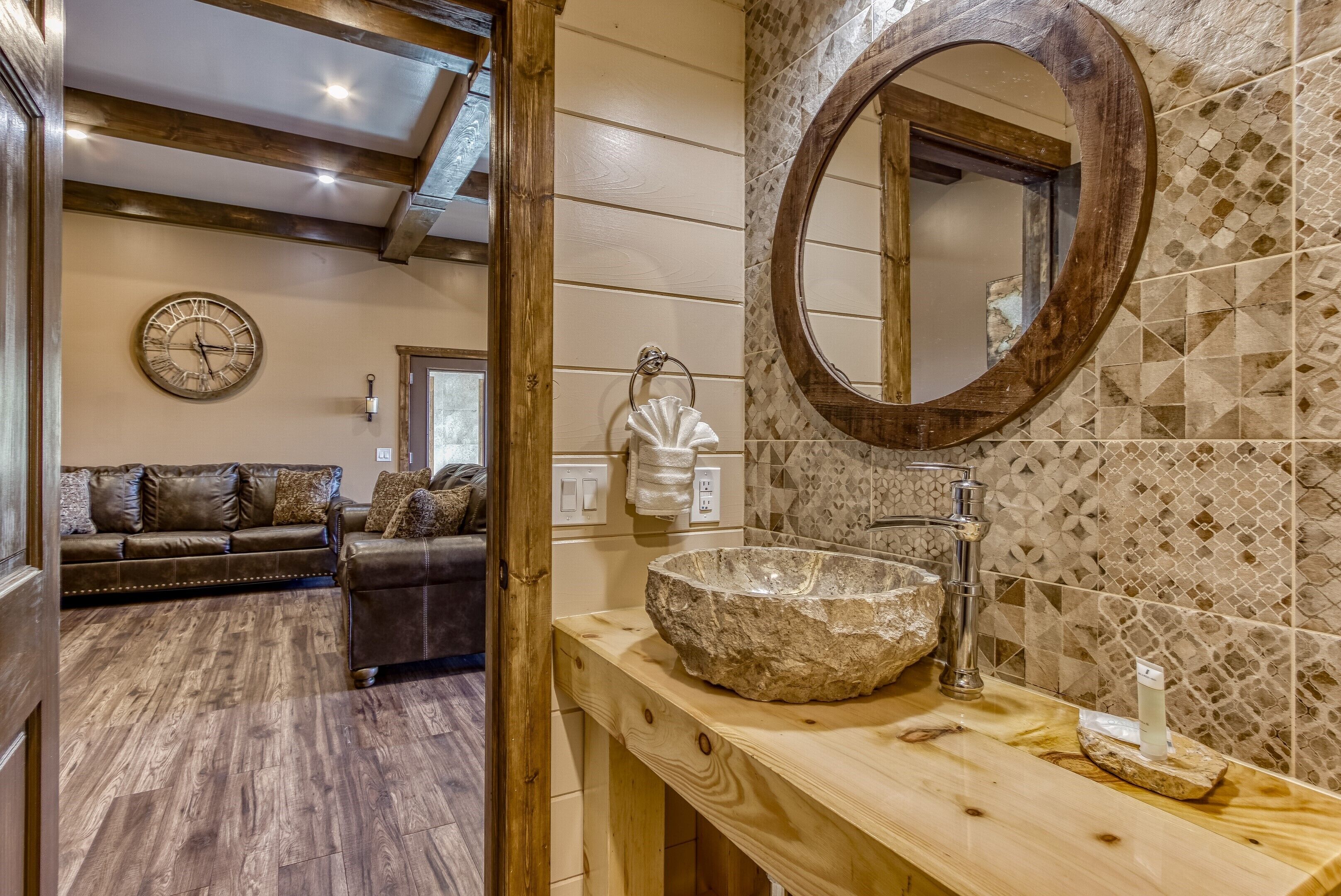 Un baño con lavamanos de piedra, tocador de madera y espejo con marco de madera.
