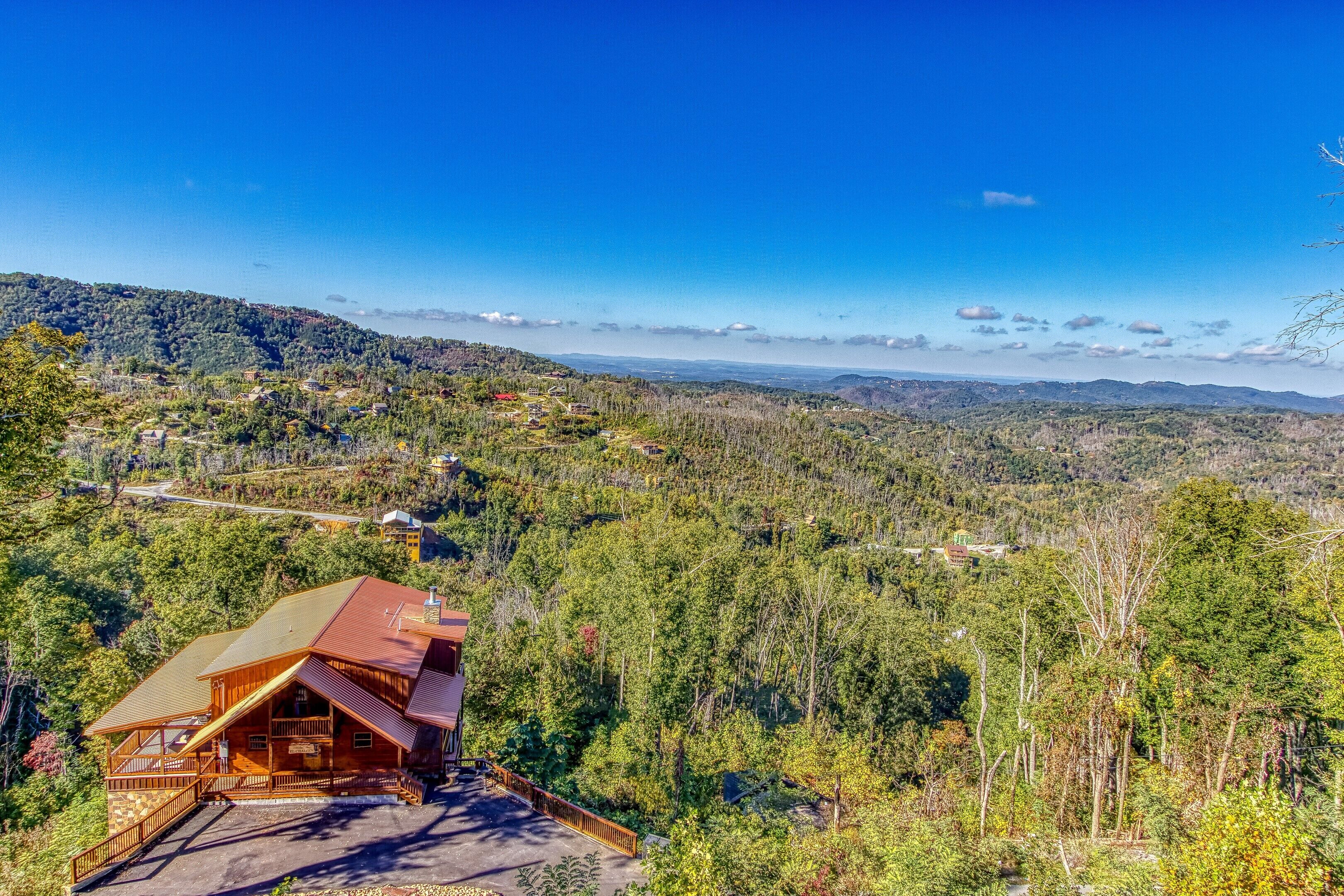 Una cabaña con una estructura de madera destacada, rodeada de un bosque denso y montañas al fondo.