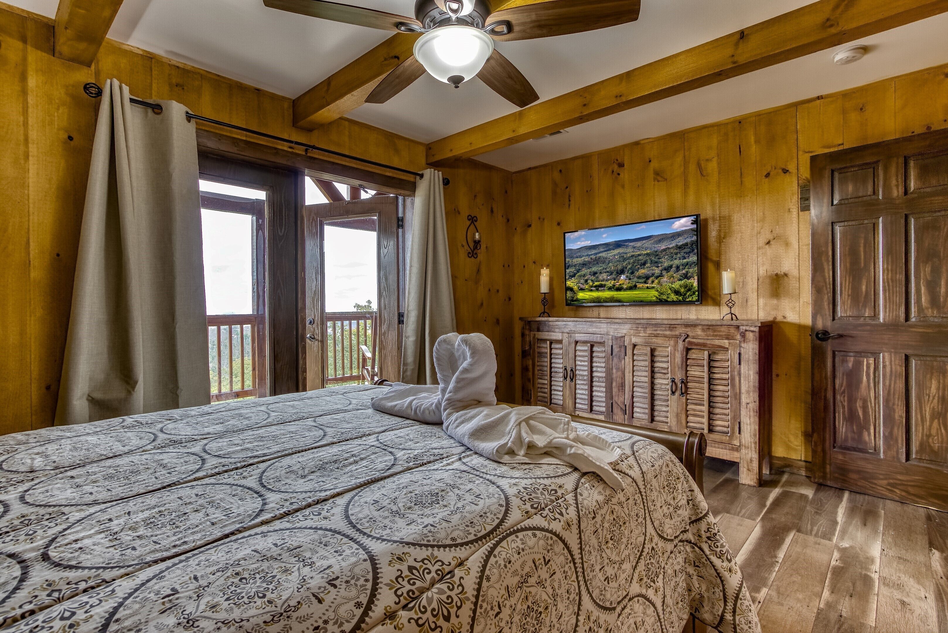 A wooden room with a bed, a television, and a fireplace.