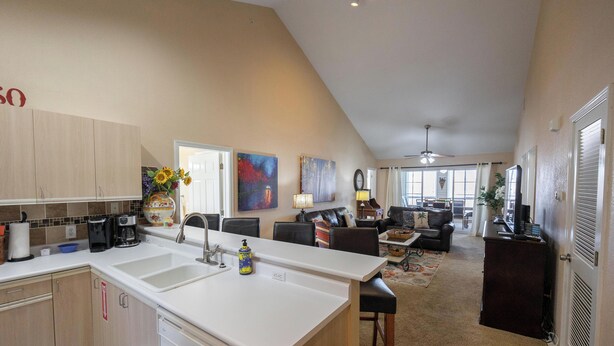 A kitchen with a large island, a dining area with a table and chairs, and a living room with a couch and a TV.