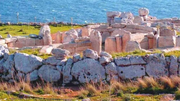 En arkeologisk plats vid kusten med stenruiner och utsikt över havet.