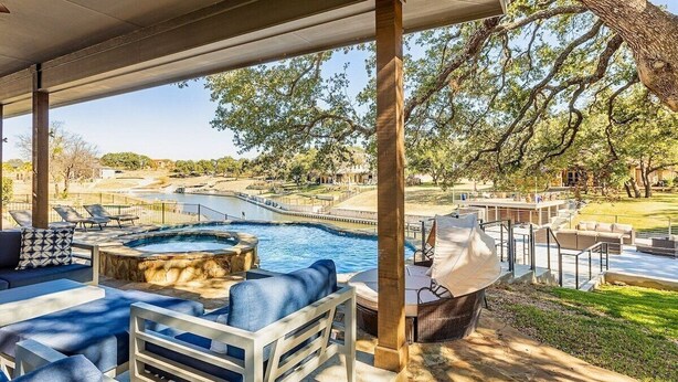 A covered outdoor area with a pool, lounge chairs, and a hot tub.