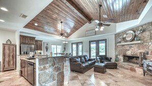 A spacious living area with a stone island, leather sofas, and a stone fireplace.
