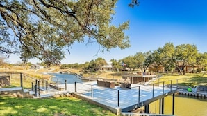 A riverside park with a wooden deck, benches, and a small bridge.