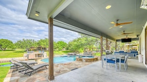 An outdoor patio with a pool, lounge chairs, a hot tub, and a bar area.