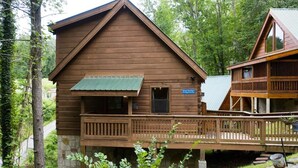 A wooden cabin with a balcony, surrounded by trees.