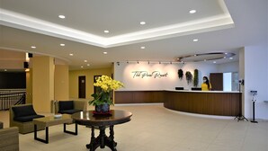 A reception area with a reception desk, a round table with a vase of yellow flowers, and a seating area with sofas and chairs. - The Pines (Raub)