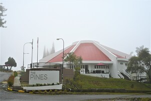 Um edifício com telhado vermelho e uma placa com a inscrição 'The Pines'.