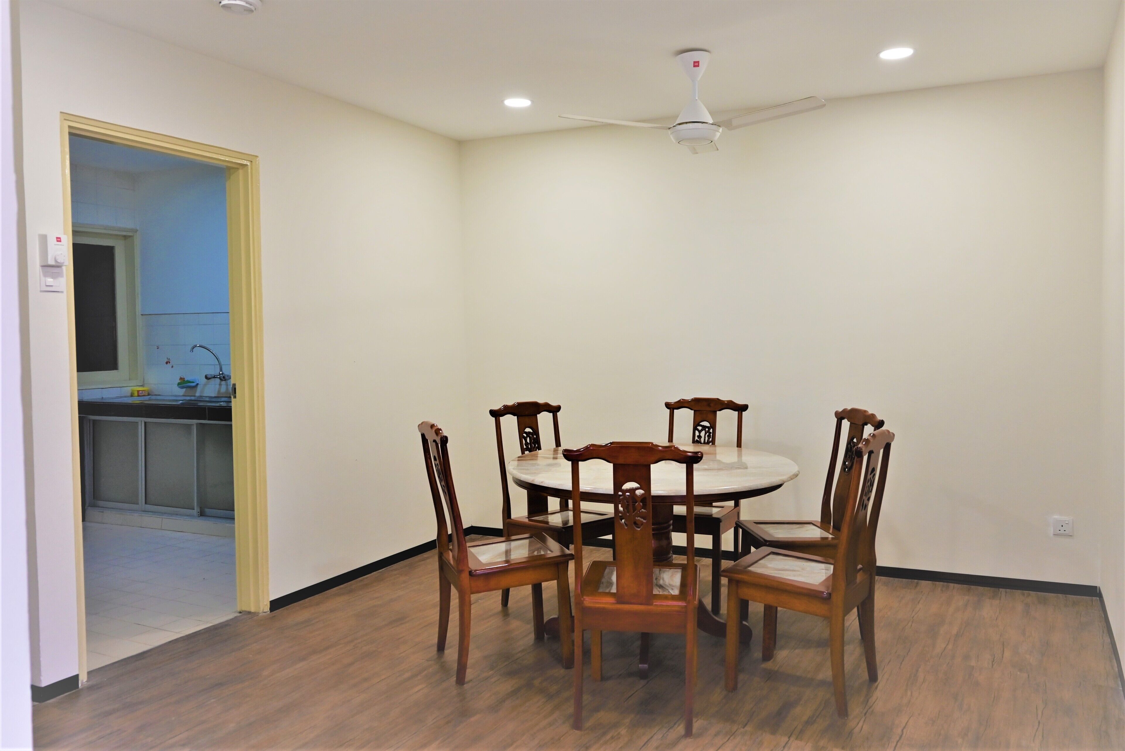 A dining area with a round table and six wooden chairs, a ceiling fan, and recessed lighting.
