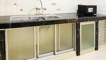 A kitchen with a black countertop, stainless steel sink, and a microwave.