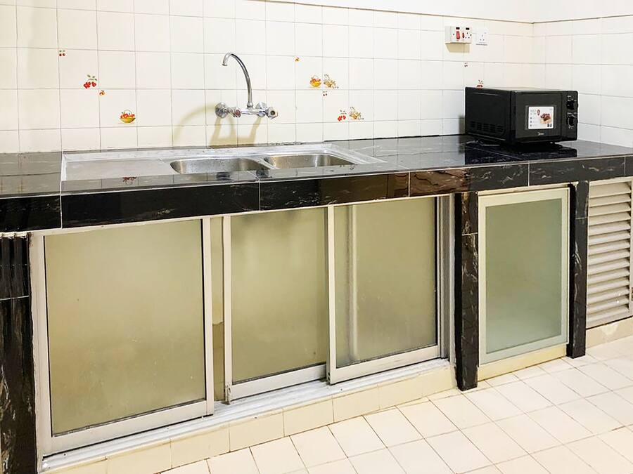 A kitchen with a black countertop, stainless steel sink, and a microwave.
