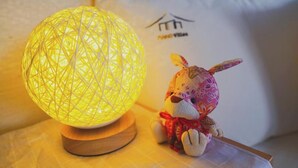 A decorative lamp with a geometric pattern and a plush toy beside it.
