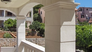 A covered outdoor area with stone columns and a view of surrounding buildings. - Antique Apartment With Balcony (Stari Grad)