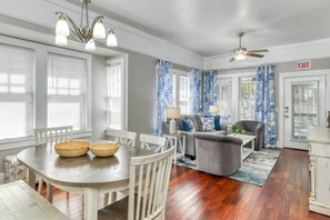 A spacious living area with a dining table, chairs, a sofa, and a ceiling fan.