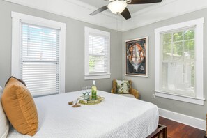 A bedroom with a bed, a ceiling fan, and a window with blinds.