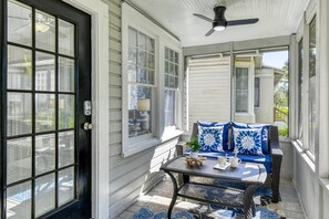 Relaxed outdoor nook featuring vibrant blue cushions, patterned rug, ceiling fan, and direct entryway access.