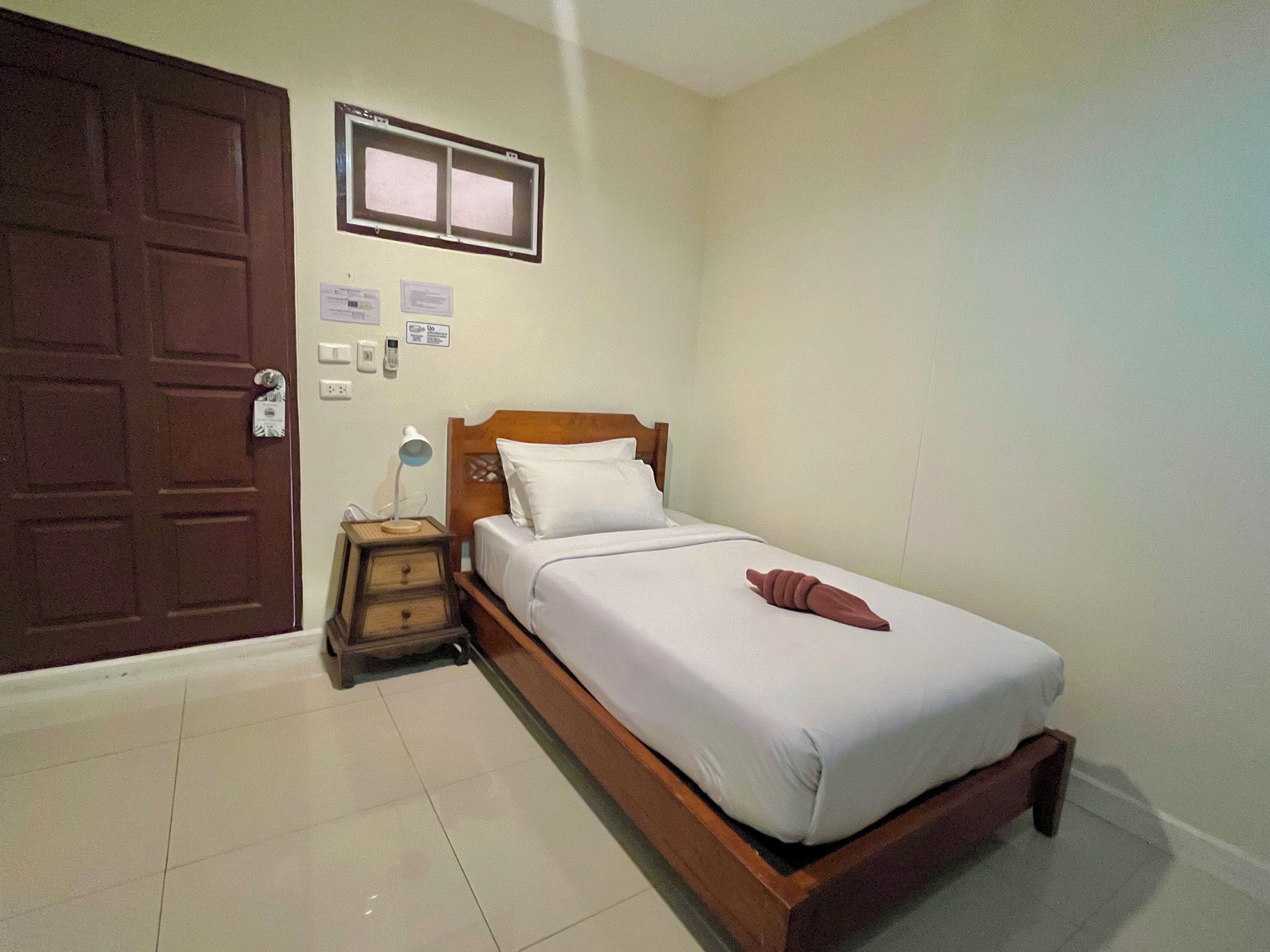 A bedroom with a wooden bed, a nightstand, a desk lamp, and a door with a window.