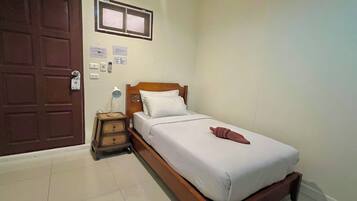 A bedroom with a wooden bed, a nightstand, a desk lamp, and a door with a window.