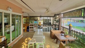 A cafe with outdoor seating, a kitchen area, and a view of greenery. - Baan Baramee House (Chiang Rai)
