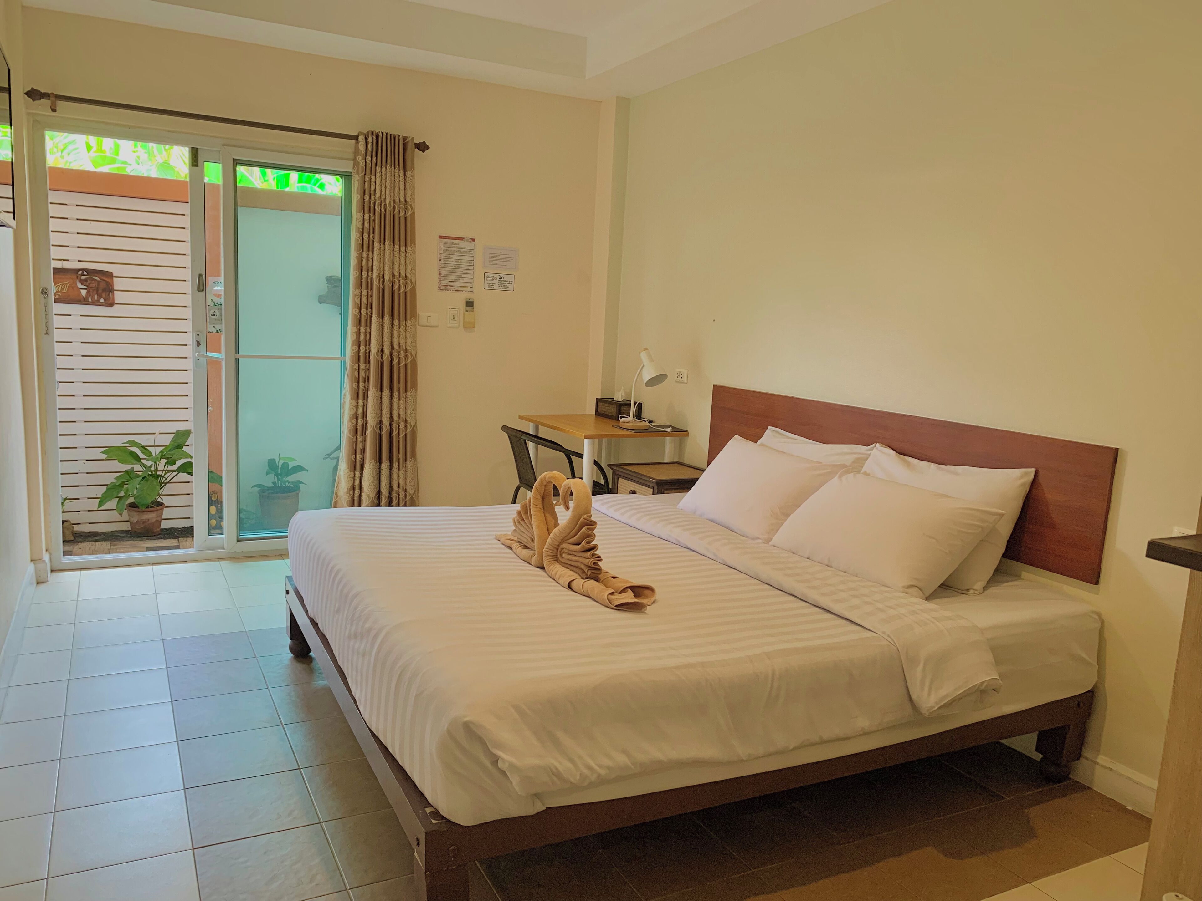 A hotel room with a bed, a desk, a chair, and a view of the outside.