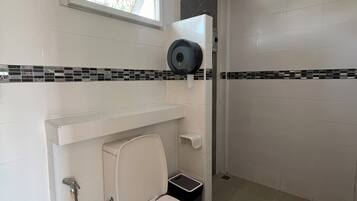 A bathroom with a toilet, a shower, and a window.